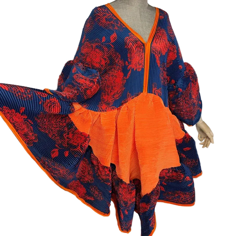 Close-up of the floral pleated dress with its navy skirt pulled outward to show the orange panel.
