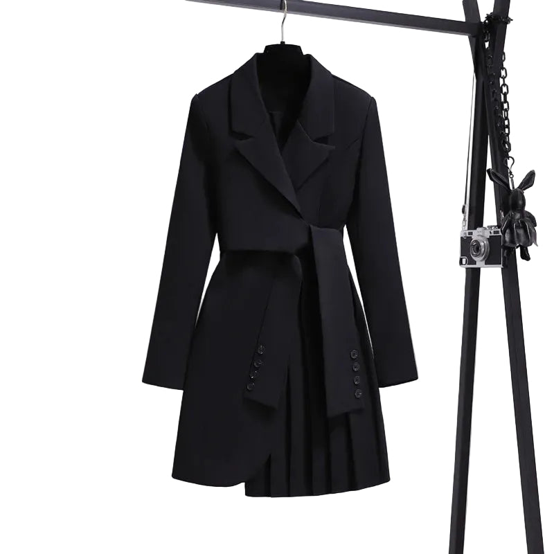 Black blazer-style dress with notched lapels, sleeve-like waist ties, and an asymmetric pleated skirt on a hanger.