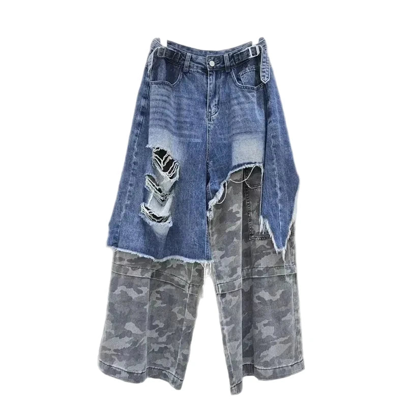 Distressed blue jeans with gray camouflage lower panels, cargo pockets, and side waist buckles, front view.