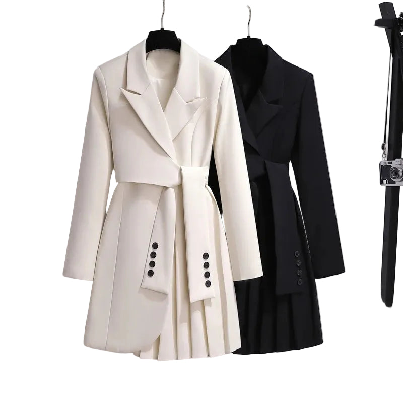 Ivory and black blazer-style dresses with sleeve-like waist ties and asymmetric pleated skirts on hangers.