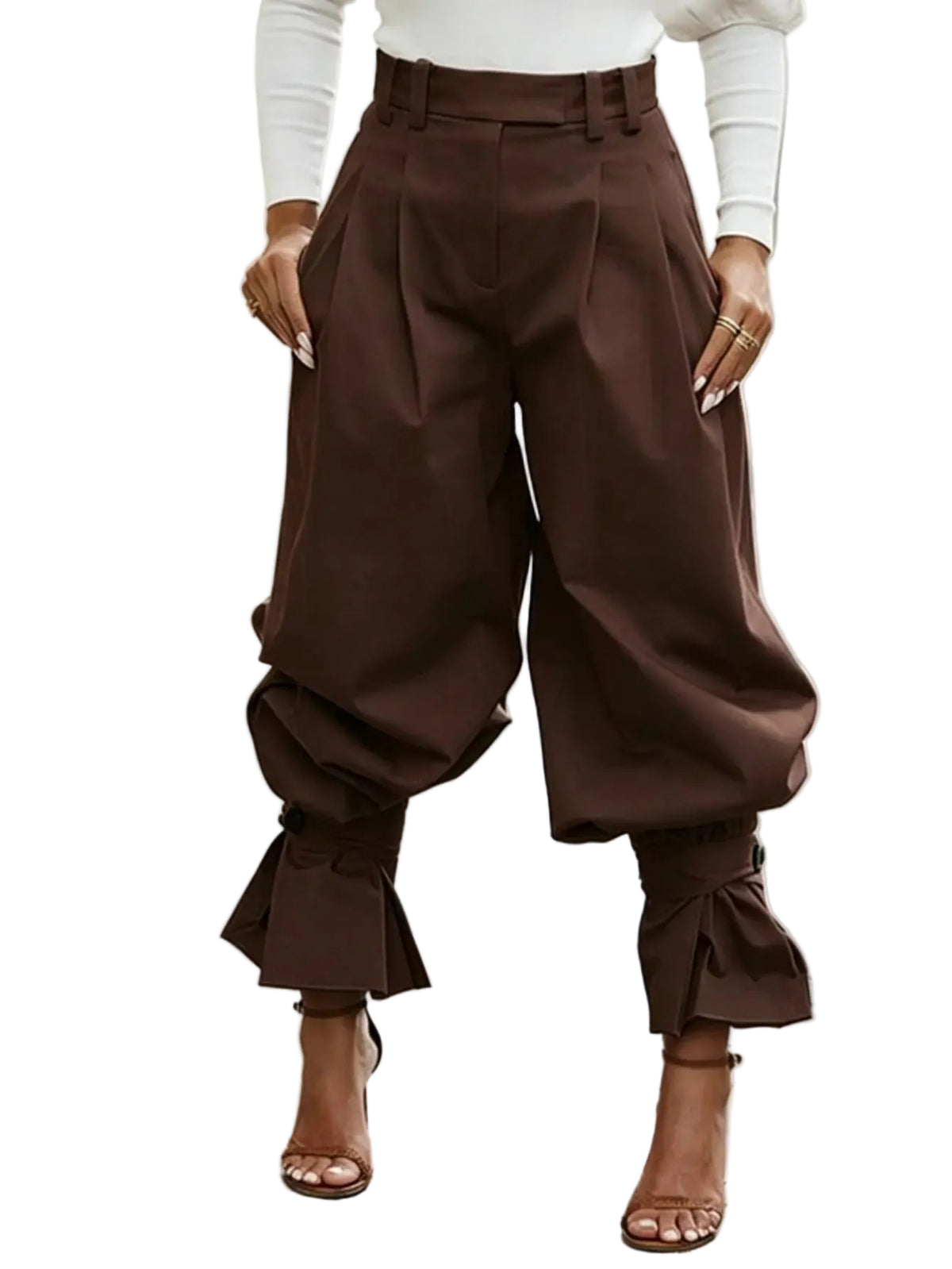 A person wearing high-waisted brown balloon-style pants with gathered cuffs and ruffled hems, paired with a white long-sleeve top and brown heeled sandals, standing on a paved outdoor walkway.