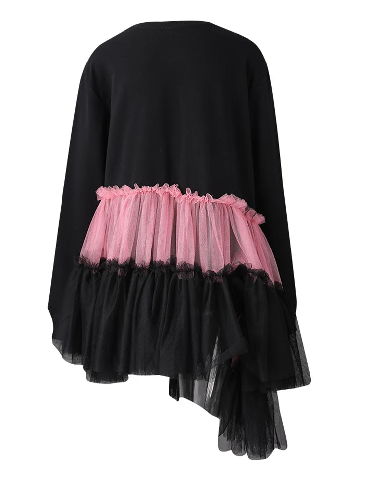 Back view of a black long-sleeve dress with pink and black tiered tulle ruffles and an asymmetric hem.