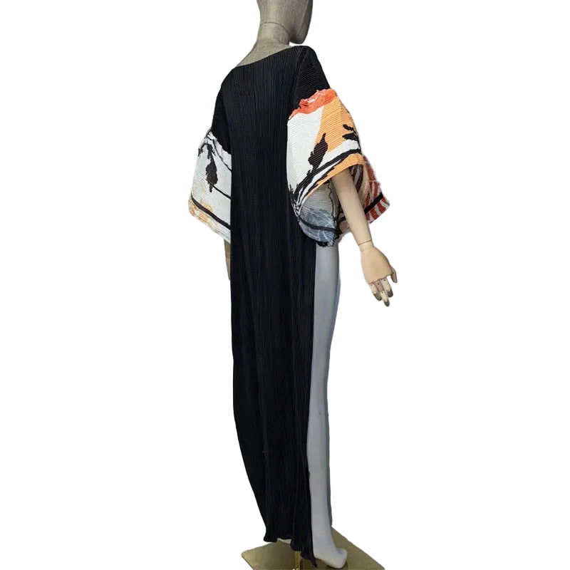 Side view of a black floral pleated top on a mannequin, showing the long back panel and wide sleeves.