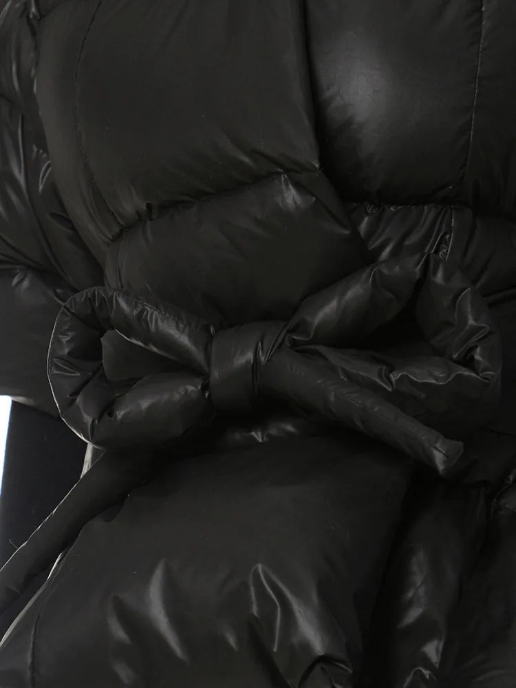 Close-up of the black padded jacket's knotted waist tie and quilted panels.