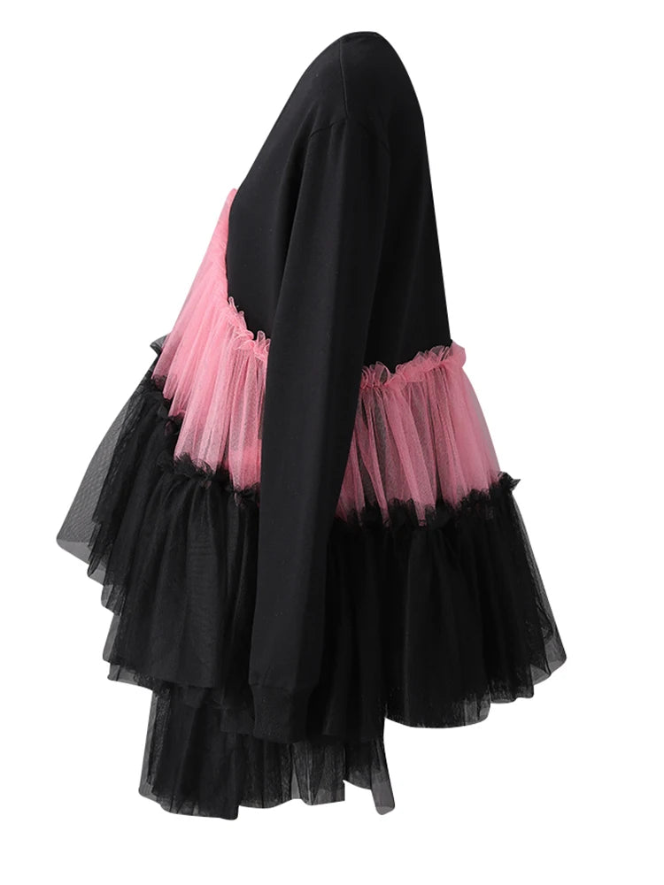Side view of a black long-sleeve dress with asymmetric pink and black tiered tulle ruffles.
