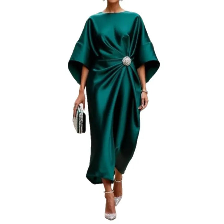 Model wearing a green satin-look draped midi dress with wide sleeves and a sparkling waist brooch, front view.