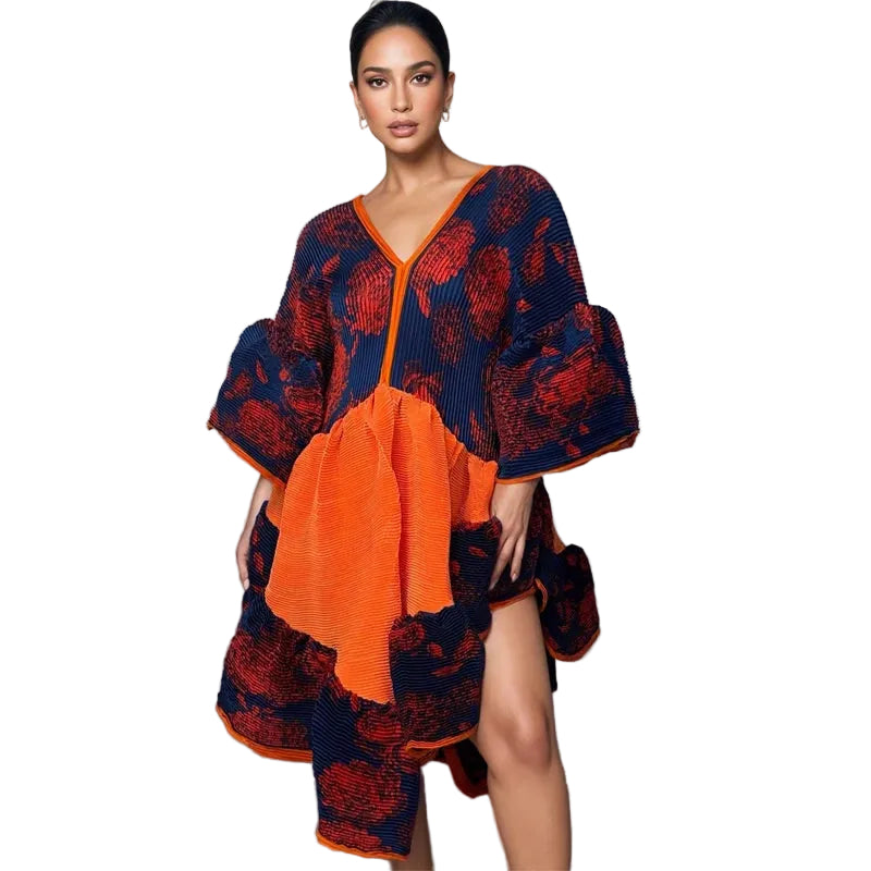 Model wearing a navy and red floral pleated dress with an orange front panel and irregular hem, front view.