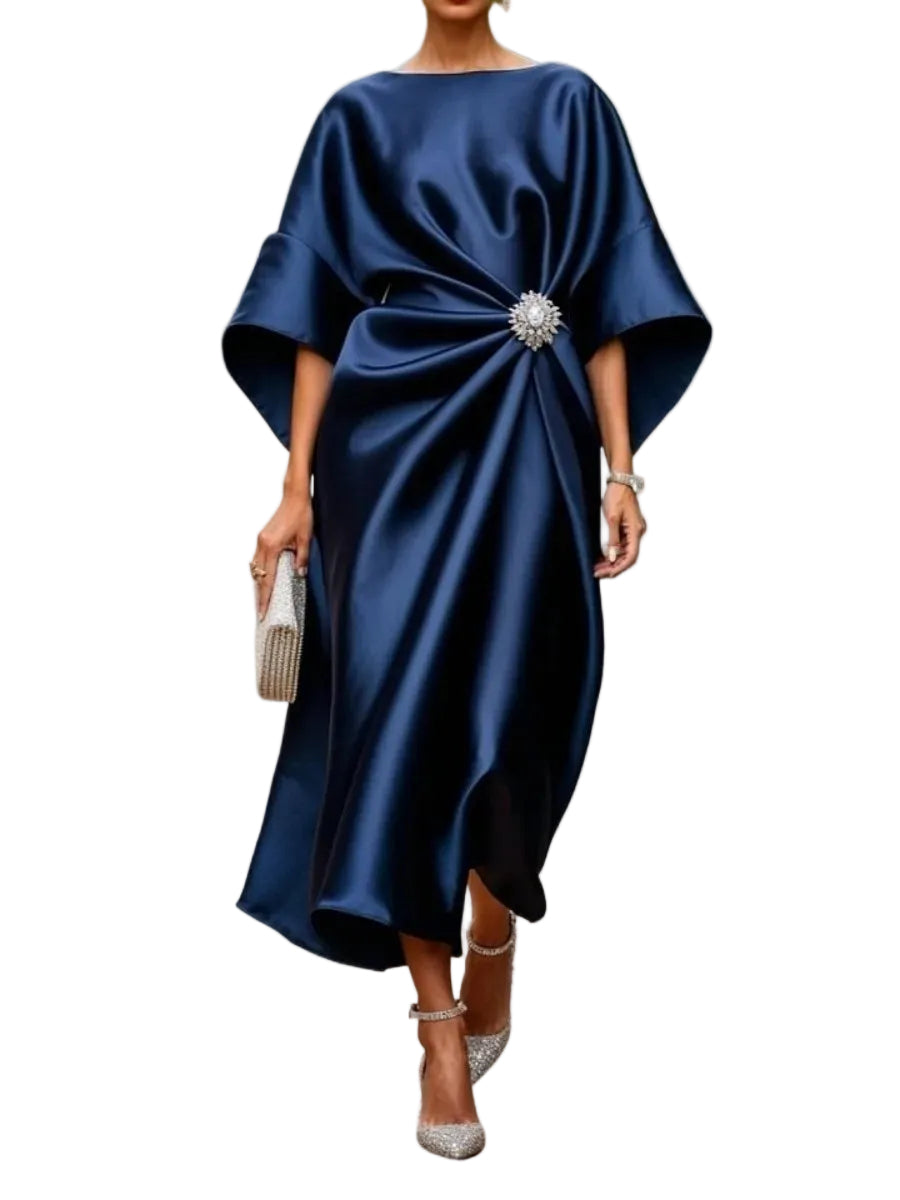 Model wearing a navy satin-look draped midi dress with wide sleeves and a sparkling waist brooch, front view.