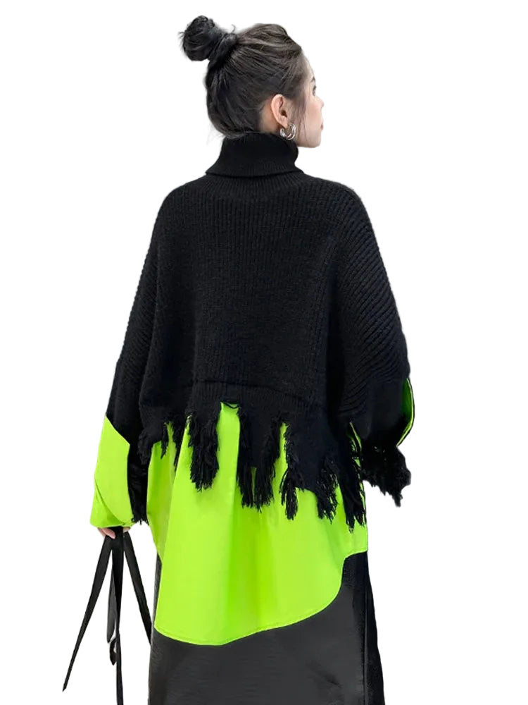 Person wearing a black and neon green outfit with tassels, standing in a modern indoor setting.