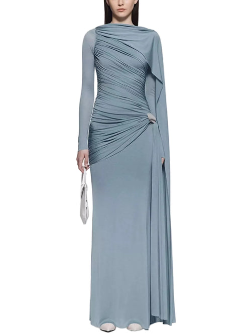 Model wearing a dusty blue long-sleeve ruched gown with a draped shoulder panel and silver hip accent, front view.