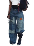 Model wearing blue wide-leg jeans with oversized patchwork pockets and contrast denim panels, front view.
