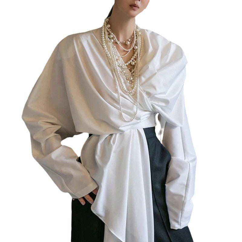 Model wearing a white draped long-sleeve wrap top with a deep V-neck and long asymmetric waist tie.