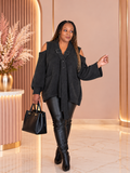 Model wearing a dark gray cold-shoulder sweater with long sleeves and crossed buckle straps at the V-neck.
