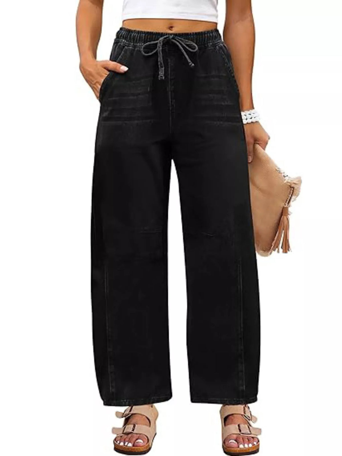 Model wearing black wide-leg jeans with a drawstring elastic waist and curved leg seams, front view.
