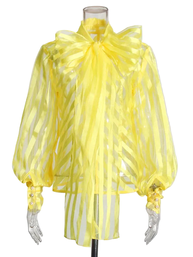 Yellow sheer striped blouse with an oversized neck bow and balloon sleeves on a mannequin, front view.