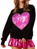 Model wearing a black long-sleeve sweatshirt with a pink metallic heart edged in pearl-like beads, front view.