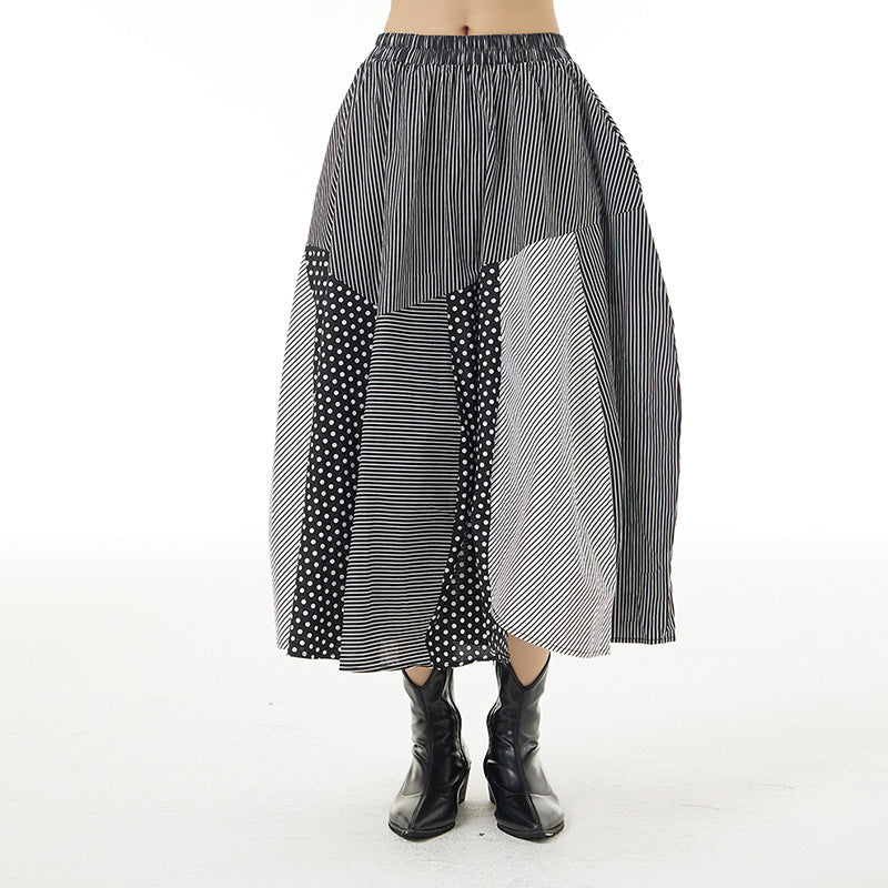 Model wearing a black and white patchwork midi skirt with striped and polka-dot panels, front view.