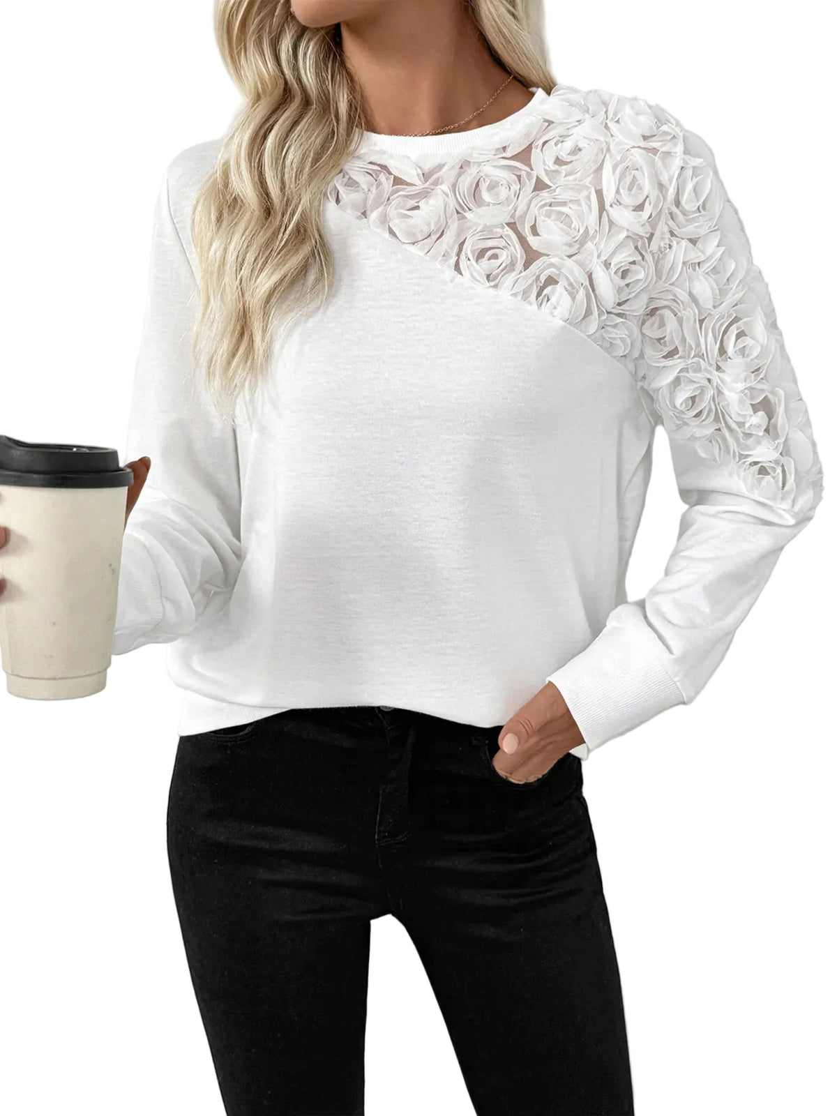 Model wearing a white sweatshirt with raised roses on one shoulder and sleeve, holding a coffee cup.