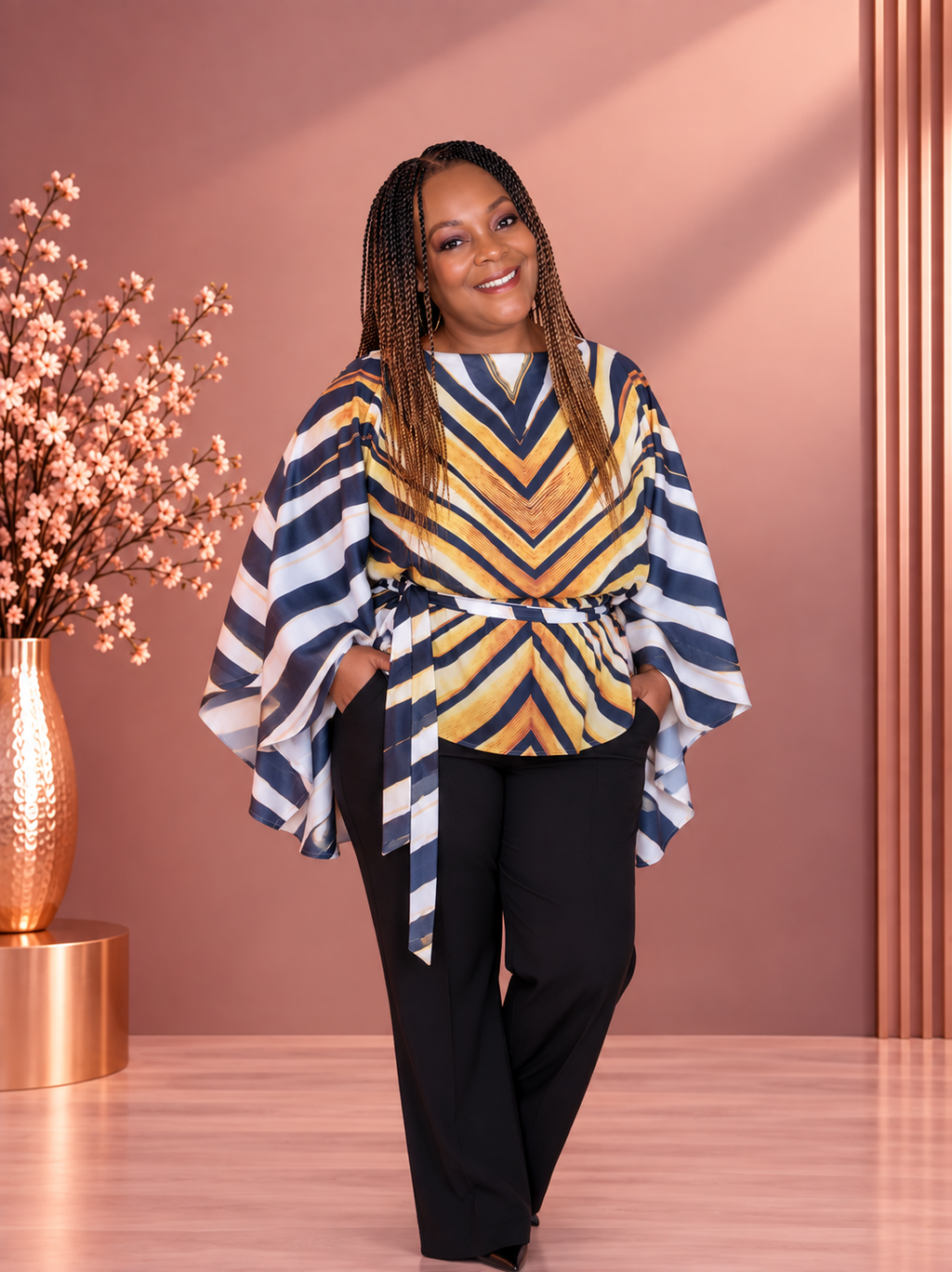 Model wearing a navy, white, and gold chevron-striped draped top with a waist tie and wide sleeves.