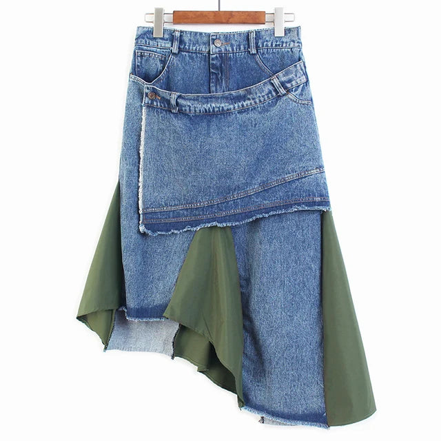 Blue patchwork denim skirt with an angled waistband overlay, raw edges, and olive green panels, front view.