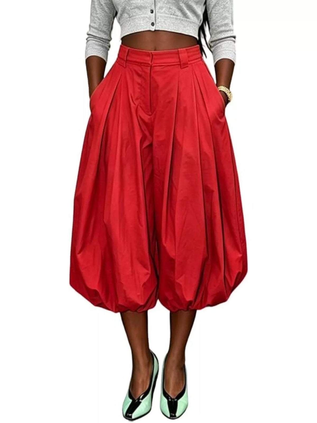 Model wearing red high-waist balloon pants with deep front pleats and gathered cropped hems, front view.