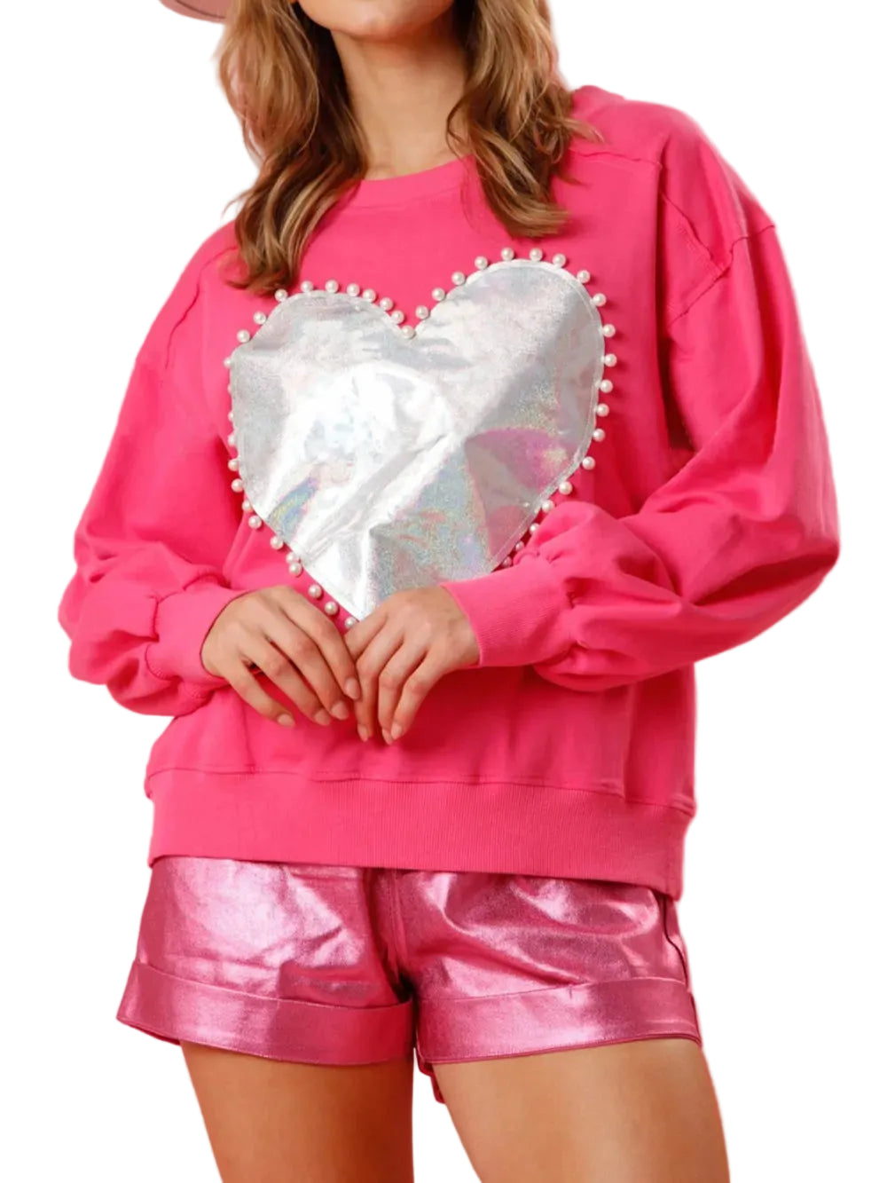 Model wearing a pink long-sleeve sweatshirt with a silver metallic heart edged in pearl-like beads, front view.
