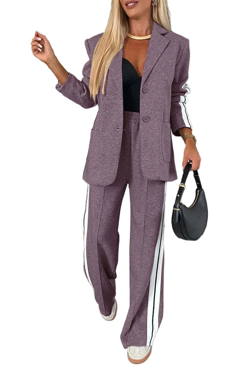 Model wearing a purple blazer and wide-leg pants with white striped sleeve and leg panels, front view.