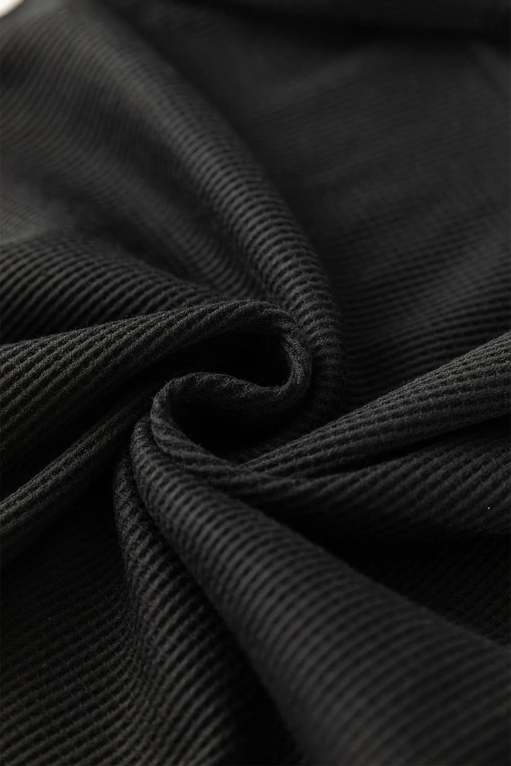 Close-up of black ribbed blouse fabric arranged in a swirl.