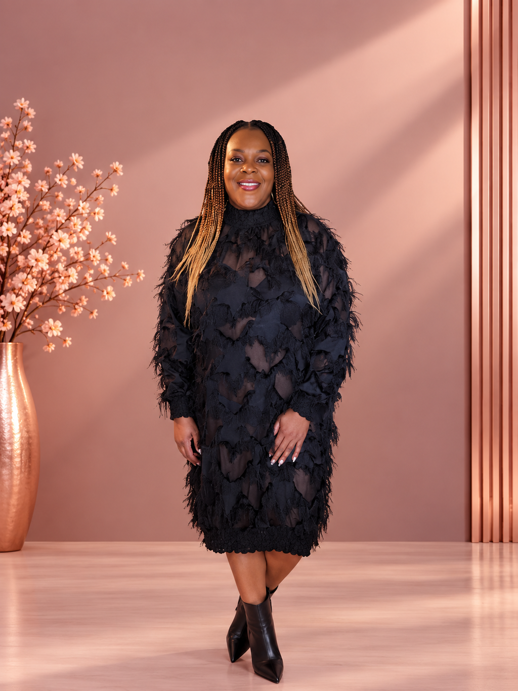 Model wearing a black long-sleeve high-neck dress with sheer panels and feathery fringe, front view.