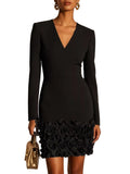Model wearing a black long-sleeve V-neck mini dress with raised roses covering the lower skirt, front view.