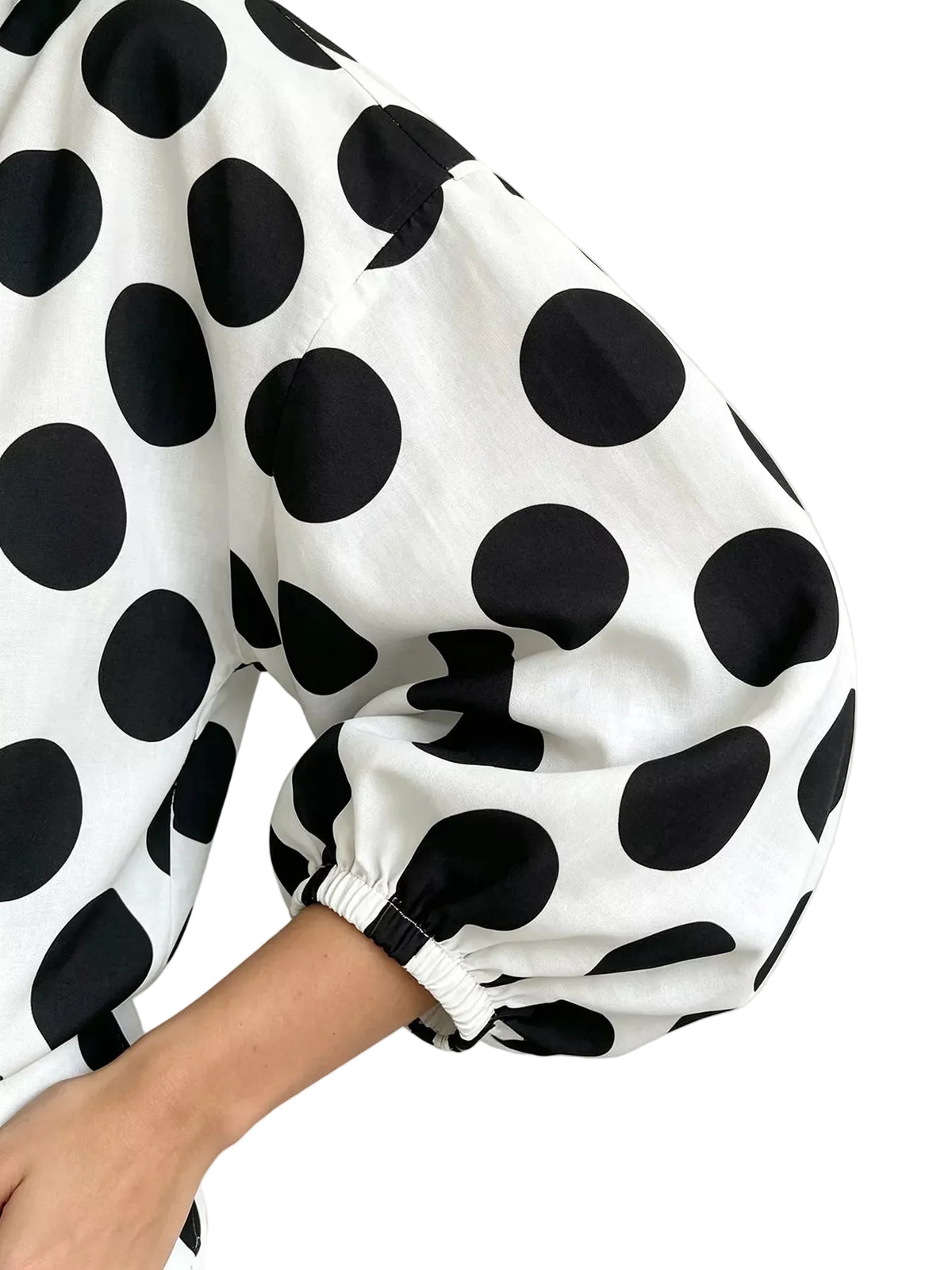 Close-up of the white polka-dot shirt's puff sleeve and gathered elastic cuff.