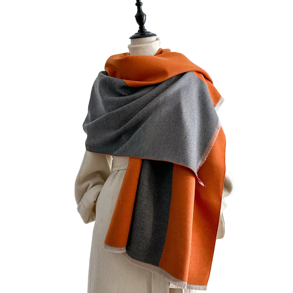 Orange and gray two-tone scarf with short fringe wrapped around a mannequin's shoulders.