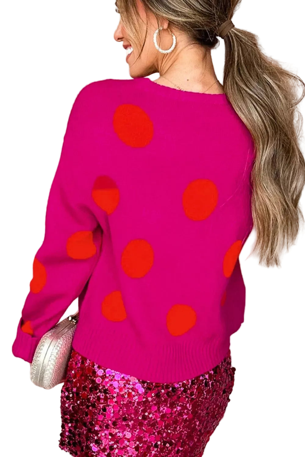 Back view of a bright pink crewneck sweater with oversized orange polka dots.