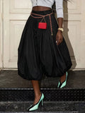 Model wearing black high-waist balloon pants with pleats and gathered hems, styled with a chain belt.