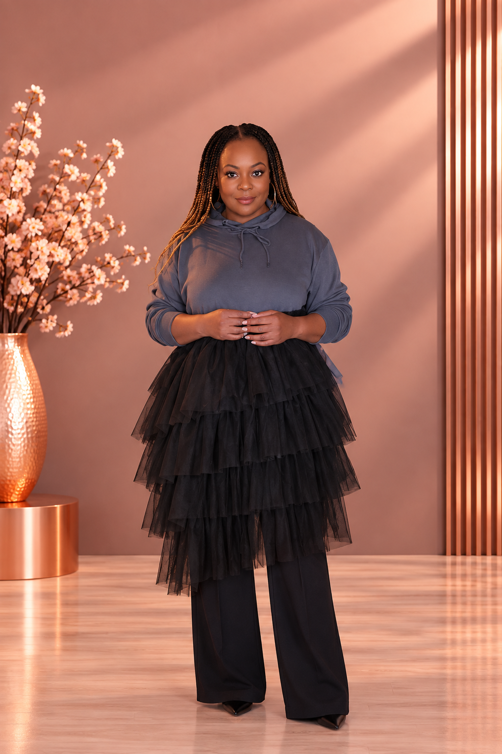 Model wearing a gray hoodie dress with a black tiered tulle skirt over black wide-leg pants, front view.