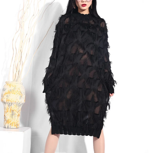 Model wearing a black high-neck dress with sheer panels, feathery fringe, and scalloped cuffs and hem.